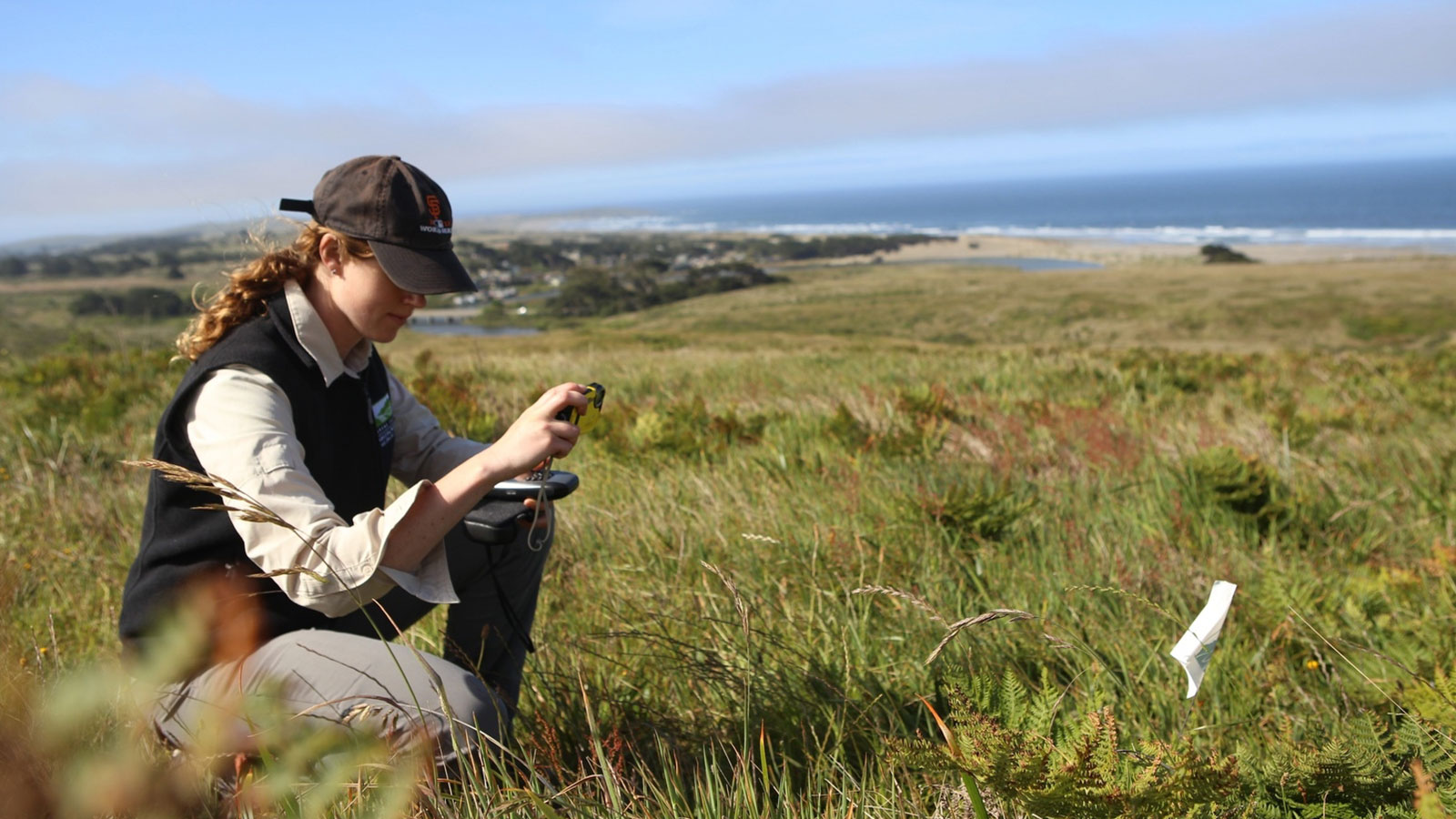 Staff member crouched in a field taking a photo at Carrington Coast Ranch