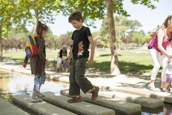 Two children cross a stream atop a set of concrete steps.