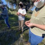 Close up staff and community members braiding cordage.