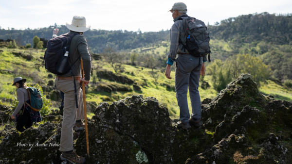 Two men stand on rock outcropping overlooking grassland