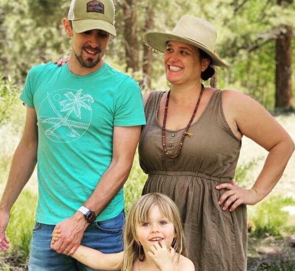 Fraser and his wife and daughter posing for the camera, while out on a hike in a green landscape. 