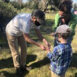 A former Ag + Open Space staff member helps a young community member practice braiding cordage.