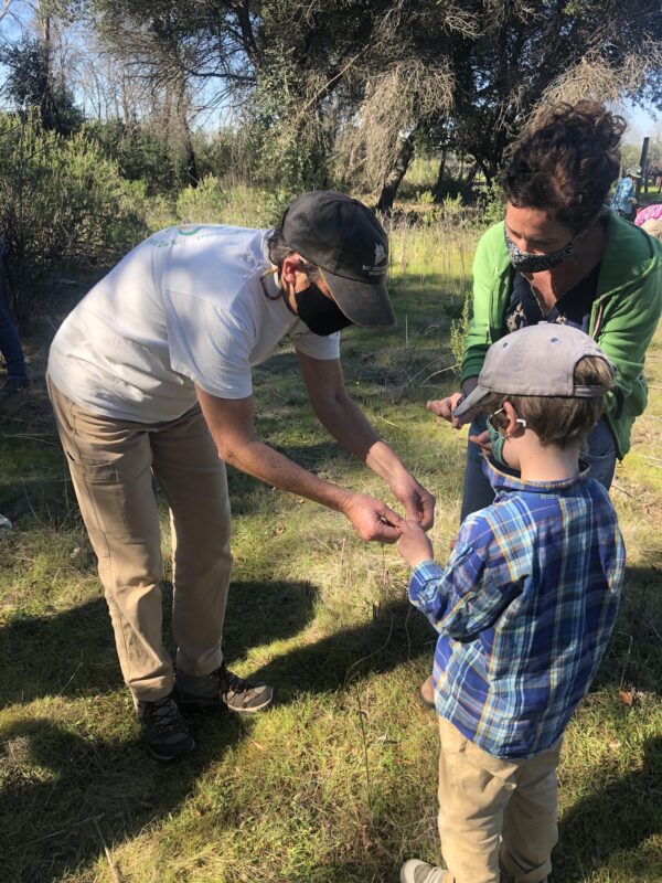 A former Ag + Open Space staff member helps a young community member practice braiding cordage.
