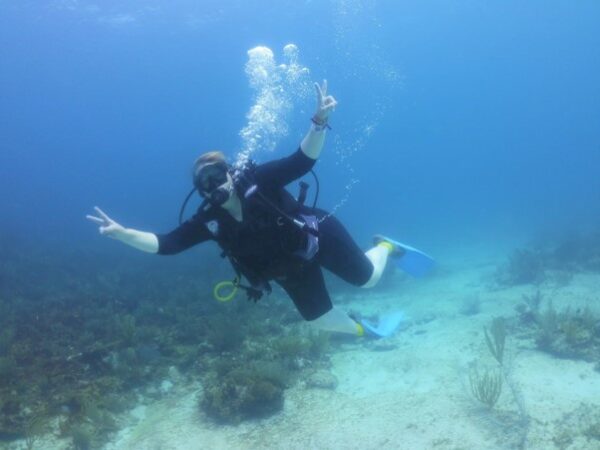 Julie scuba diving, while making the peace sign with her hands.