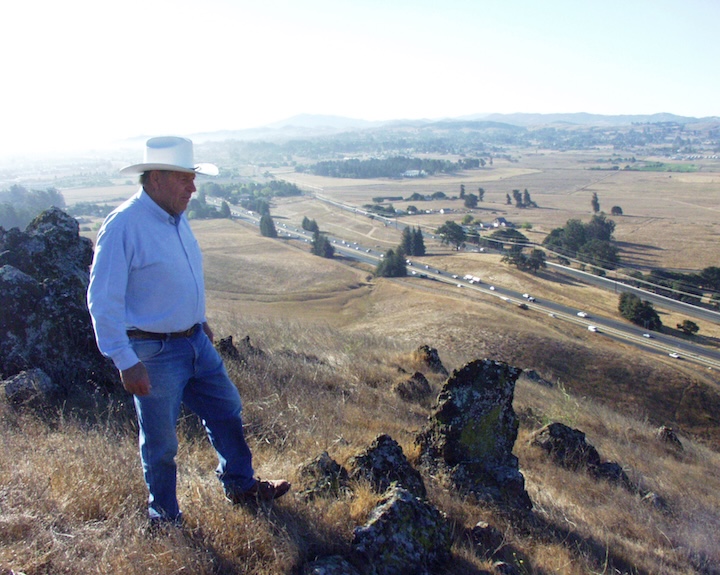 a man standing on the top of a hill looking down at the road way