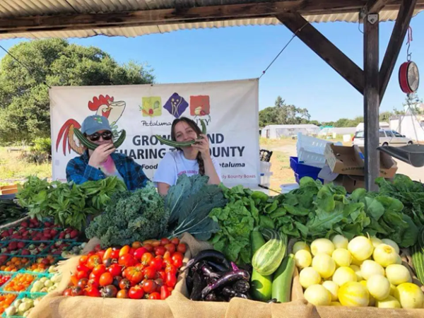 Women at Bounty Farms use veggies to make smiley face on themselves. Veggies in foreground