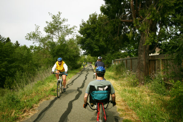 Two people on bikes, going in different directions on paved pathway.