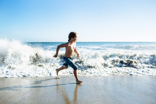 Young boy plays in the waves at the ocean,