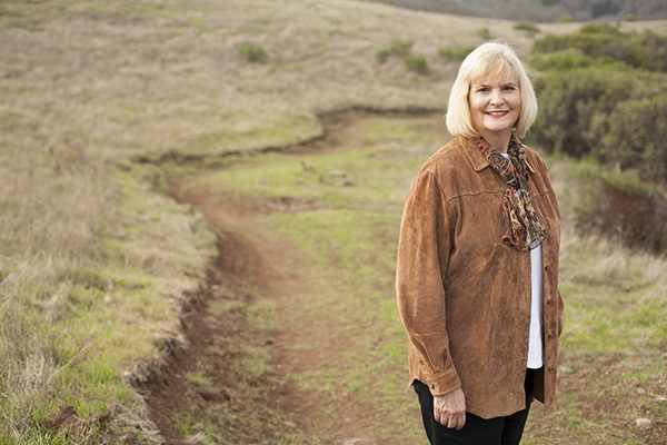 Supervisor Susan Gorin standing on a trail beside a golden field. 