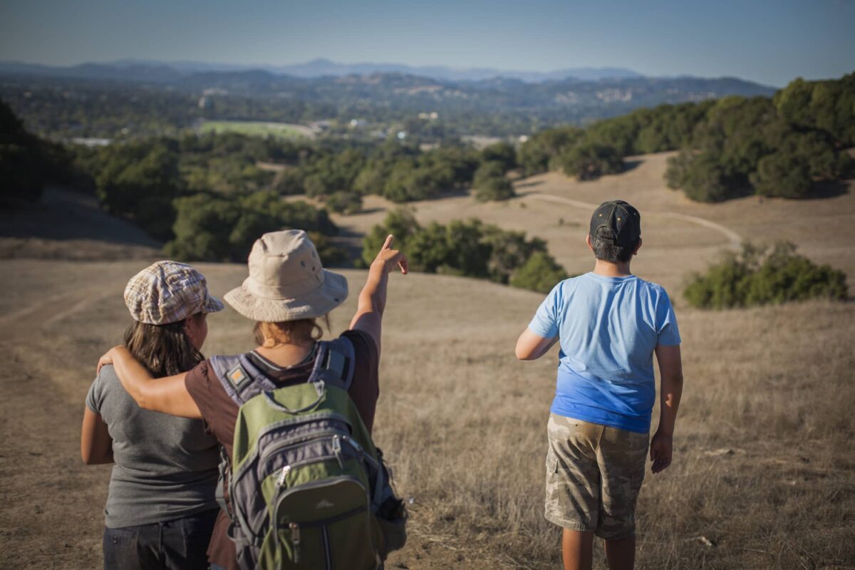 three people at the top of a hill