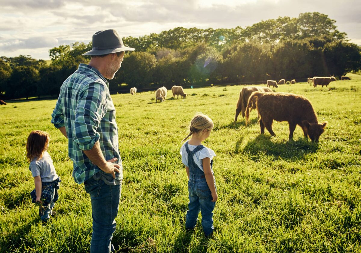 Shot of a father and his two little children watching over cattle on a farm